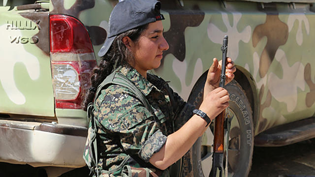 ​Kurdish fighter Akina Akin cleans her weapon after clashes with ISIS militants in Mahmoodin 