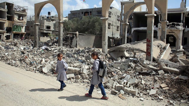 Palestinian girls walk past the rubble of a building which was destroyed during the Israeli army summer's military offensive on the Gaza Strip 