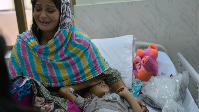 Pakistani woman sits with son wounded in India-Pakistan border violence 