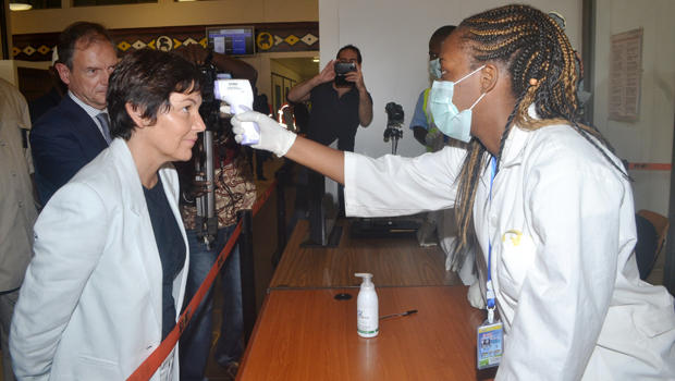 A health employee takes the temperature of France official Annick Girardin, left, during a health inspection upon her arrival at the airport in the Guinean capital of Conakry Sept. 13, 2014. 