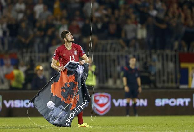 Stefan Mitrovic of Serbia grabs a flag depicting so-called Greater Albania that was flown over the pitch during their Euro 2016 Group I qualifying soccer match against Albania at the FK Partizan stadium in 