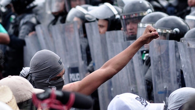 Masked protester makes fist at police in Acapulco 