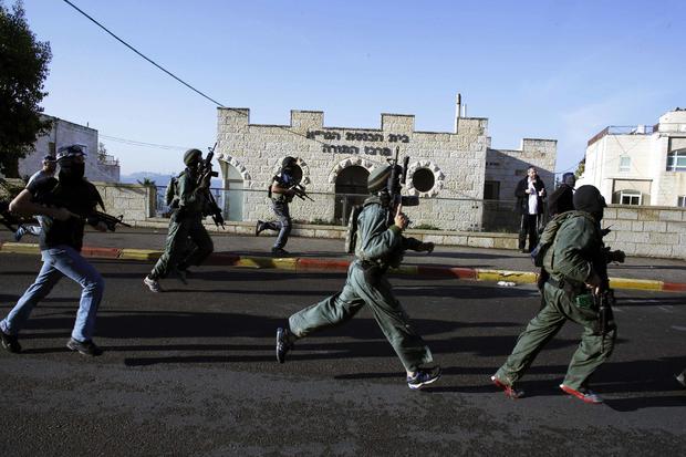 Israeli security personnel run next to a synagogue, where an attack took place in west Jerusalem 
