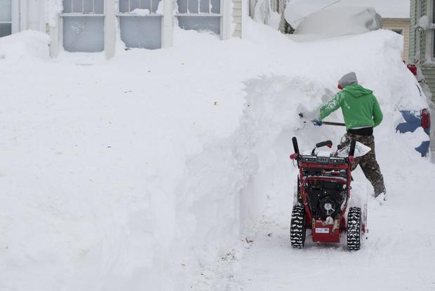A man works to clear snow covering his vehicle following a storm in Buffalo, N.Y., Nov. 20, 2014. 