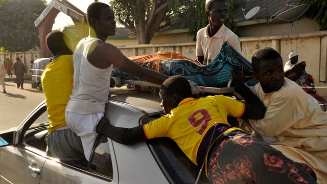 The remains of a Kano, Nigeria, bombing victim are carried on the top of a car from the Murtala Mohammed specialist hospital for burial according to Muslim rites Nov 28, 2014. 