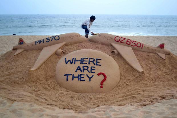 Indian sand artist Sudarsan Pattnaik gives the final touches to his sand sculpture portraying two missing aircraft, Air Asia QZ8501 and Malayasia Airlines MH370 on Golden Sea Beach at Puri, some 65 kms east of Bhubaneswar on December 29, 2014. 