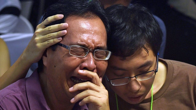 Family members of passengers from AirAsia flight QZ8501 react after watching news reports showing an unidentified body floating in the Java sea 