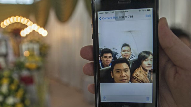 A picture on a mobile phone shows Hendra Gunawan Sawal (back C in the photograph), sitting on AirAsia Flight 8501 