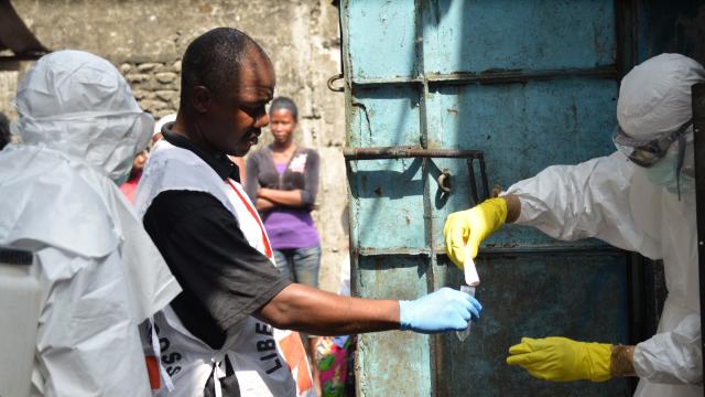 Red cross workers, wearing protective suits, prepare prior to a burial for victims of the Ebola virus, in Monrovia 