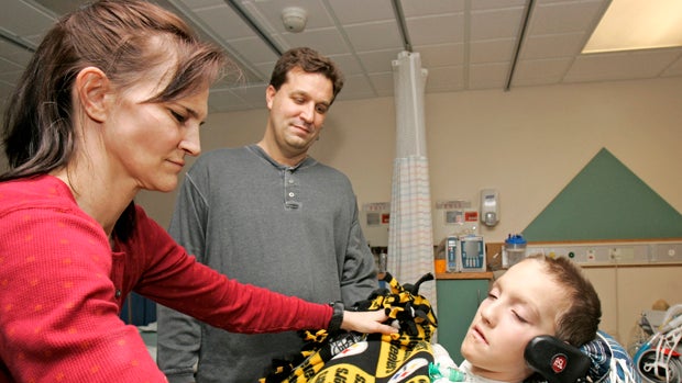 Beth Malarkey covers up her son, Alex, right, with a blanket after surgery as Alex's father, Kevin, watches at University Hospital's Case Western Reserve Medical Center in Cleveland Jan. 9, 2009. Alex Malarkey was in a 2004 car crash that left him paralyz 