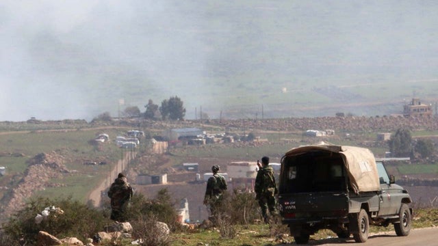 Lebanese army soldiers watch as smoke rises from shells fired from Israel over al-Wazzani area in southern Lebanon 