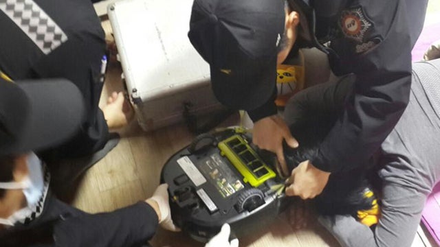 Firefighters try to rescue a woman at her house in Changwon, South Korea, after her hair became stuck in a robotic vacuum cleaner 