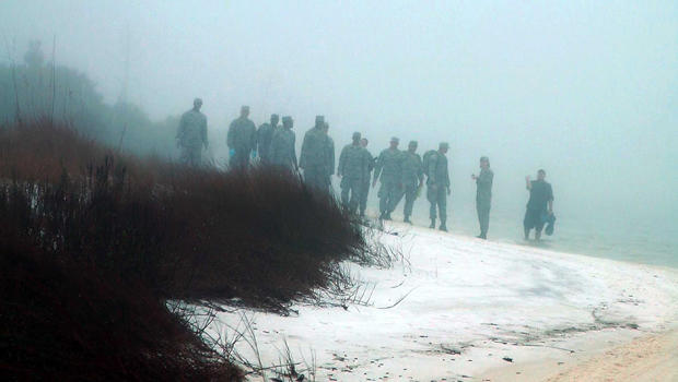 Military personnel wade in the water and search on the beach under heavy fog at Eglin Air Force Base, Florida, March 11, 2015, for the wreckage of a military helicopter that crashed with 11 service members aboard. 