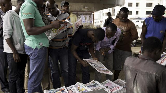 People look at newspaper headlines as they gather at a news stand at Port Harcourt 