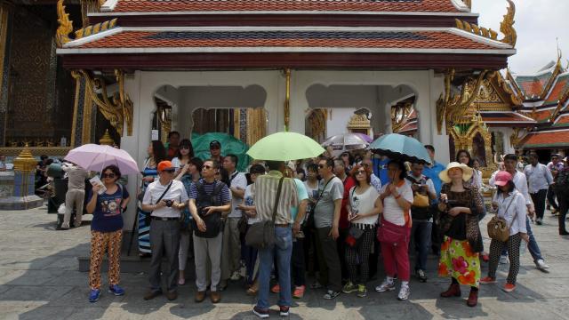 Chinese tourists listen to their guide as they visit Wat Phra Kaeo (Emerald Buddha Temple) in Bangkok.  