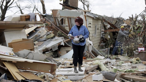 A woman holds her belongings after searching through the debris of a home that was destroyed by a tornado in Rochelle, Illinois, April 10, 2015. 