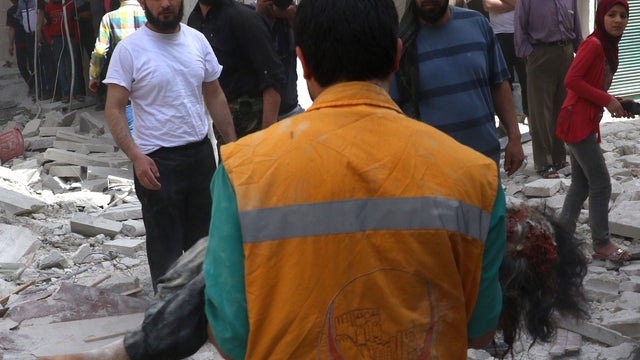 A Syrian rescue worker carries the body of a victim of a reported barrel bomb attack by Syrian government forces on a rebel-held neighborhood in Aleppo 