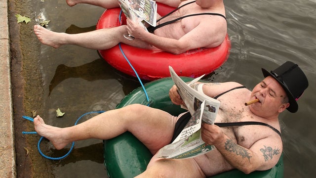 Men dressed as 'greedy businessmen' in mankinis float in the Serpentine Lake in London's Hyde Park  