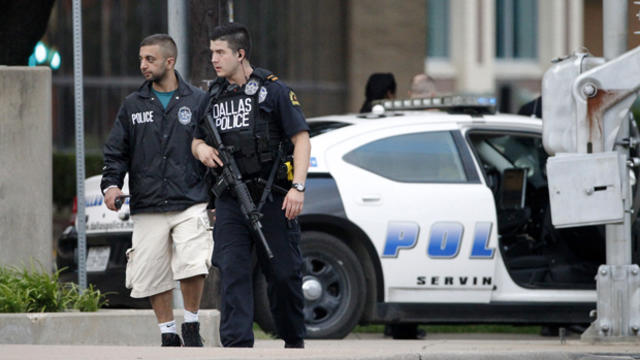 Dallas police officers walk down Belleview Street, one block away from police headquarters, searching the area June 13, 2015, in Dallas. 