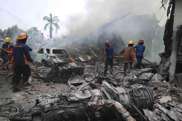 Firemen attempt to extinguish the fire surrounding the wreckage of an Indonesian military transport plane after it crashed in the North Sumatra city of Medan, Indonesia 