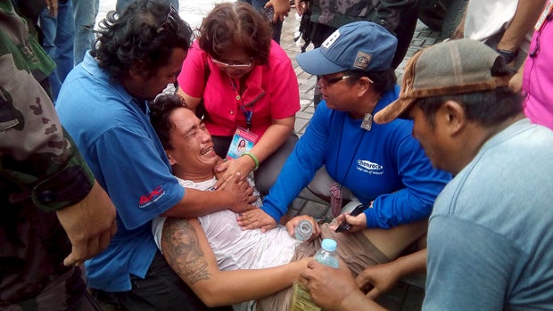 Rescuers try to calm a passenger who said his pregnant wife and two children are still missing after the MBCA Kim-Nirvana ferry capsized in Ormoc city, Philippines, July 2, 2015. 