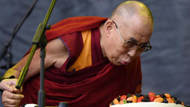The Dalai Lama blows out a candle on a cake to celebrate his 80th birthday on the Pyramid stage as he visits the Glastonbury Festival of Music and Performing Arts on Worthy Farm near the village of Pilton in Somerset, England, June 28, 2015. 