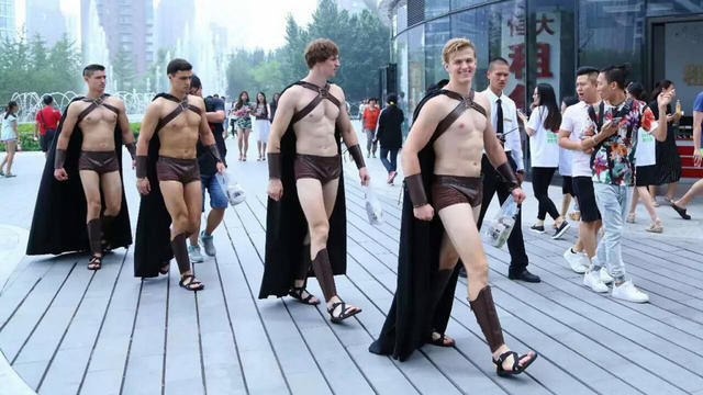 Half-naked male foreign models dressed in costumes of Spartan warriors march along a street during an anniversary promotional campaign by Chinese O2O salad provider Sweetie Salad in Beijing, China 