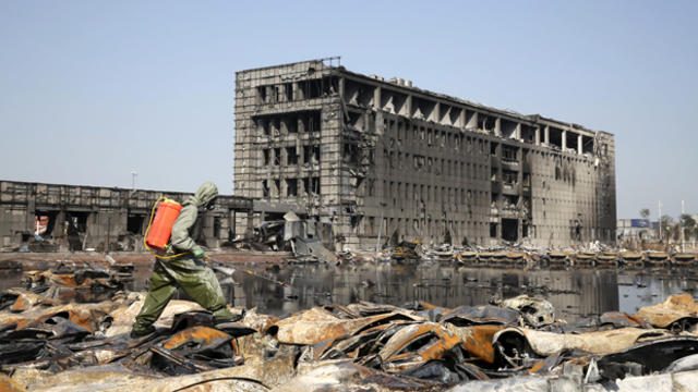 A People's Liberation Army soldier of the anti-chemical warfare corps in a protection suit sprays liquid on the debris at the site of blasts in Binhai, new district of Tianjin, China, Aug. 21, 2015. 