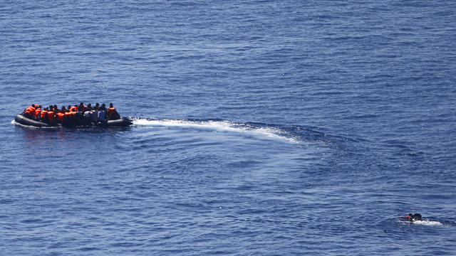 A man tries to swim towards a dinghy carrying migrants as it leaves for the Greek island of Lesbos from the southern Turkish coastal town of Behramkale in the Aegean sea between Turkey and Greece 