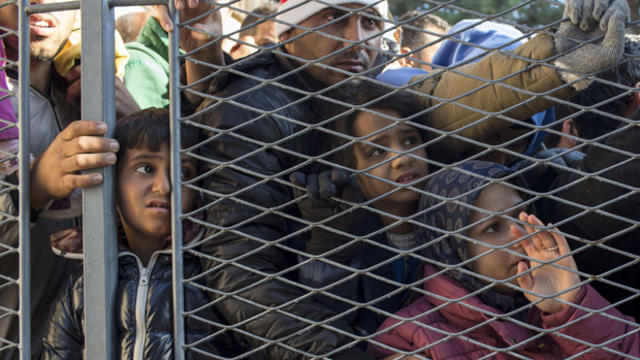 Migrants stand behind a gate as they wait to board buses inside a registration camp in Opatovac, Croatia, Sept. 23, 2015. 