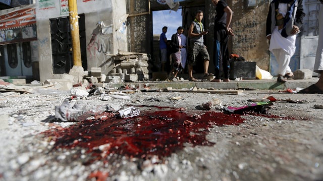 People stand outside the al-Balili mosque after two bombings at the mosque in Yemen's capital Sanaa 