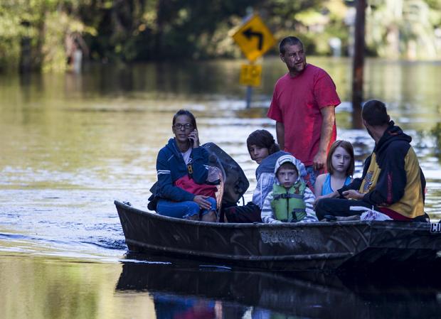 Scott Everett, standing, transports his family on a johnboat along Lee's Landing Circle in Conway, South Carolina, Oct. 7, 2015. 