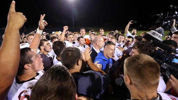 Bremerton assistant football coach Joe Kennedy, in blue, is surrounded by Centralia players after they took a knee with him and prayed after their game against Bremerton in Bremerton, Wash., Oct. 16, 2015.