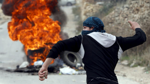 A Palestinian protester hurls stones at Israeli troops during clashes in the West Bank city of Hebron Nov. 6, 2015. 