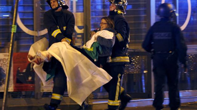 French fire brigade members aid an injured individual near the Bataclan concert hall following fatal shootings in Paris, France, Nov. 13, 2015. 