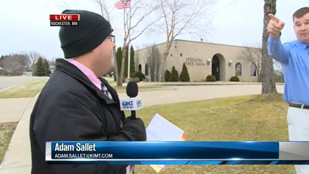A bank employee interrupts a live news report to point out a suspected bank robber in Rochester, Minn., Dec. 15, 2015. 