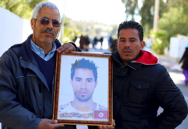 Othman Yahyaoui (L) holds a photograph of his son Ridha Yahyaoui, who committed suicide by climbing an electricity transmission tower, in Kasserine 