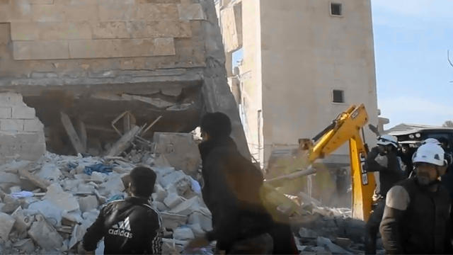 ​Members of the "White Helmets" Syrian rescue force and others climb over debris around a building that had been used as a makeshift clinic in Idlib province 