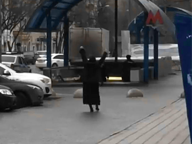 This screengrab from video posted to YouTube shows a woman who appears to be holding the severed head of a child while shouting at passersby outside the entrance to the Oktyabrskoye Pole metro station in northwest Moscow 