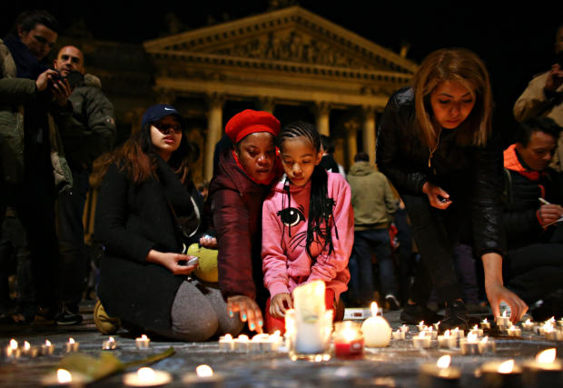 ​A young girl lights a candle at the Place de la Bourse following attacks in Brussels, Belgium, on March 22, 2016. 
