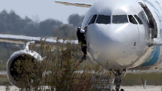 A man climbs out of the cockpit window of the hijacked Egyptair Airbus A320 at Larnaca Airport in Larnaca 