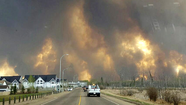 This photo taken through a car windshield shows smoke rising from a wildfire raging outside of Fort McMurray, Alberta, May 3, 2016. 