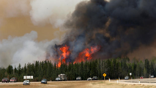 ​A wildfire burns as evacuees who were stranded north of Fort McMurray, Alberta, Canada, head south of the city on Highway 63, May 6, 2016. 