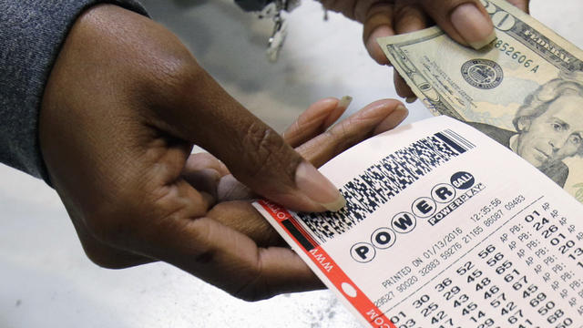 A clerk hands over a Powerball ticket for cash at Tower City Lottery Stop in Cleveland Jan. 13, 2016. 