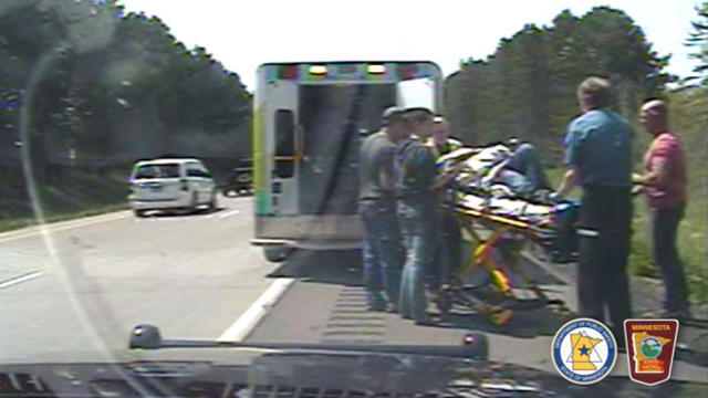 In an image capture from dashcam video, first responders treat a woman who was pulled from a car before it burst into flames on Interstate 35 near Hinckley, Minnesota, on May 8, 2016. 