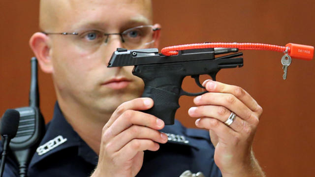 Sanford police officer Timothy Smith holds up the gun that was used to kill Trayvon Martin while testifying during George Zimmerman's murder trial in Seminole circuit court in Sanford, Florida, June 28, 2013.​ 