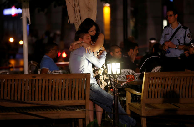 People hug each other following June 8, 2016 terror attack in Tel Aviv market 