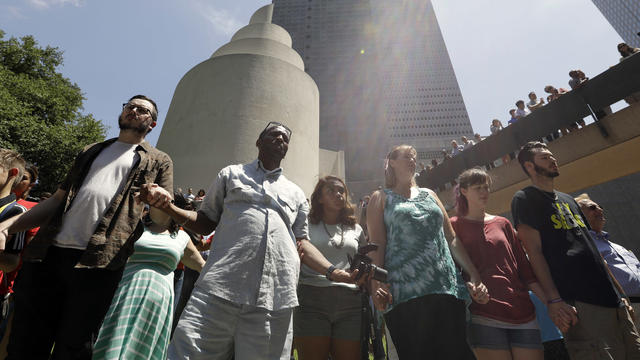People take part in a prayer vigil at Thanksgiving Square, July 8, 2016, in Dallas. 