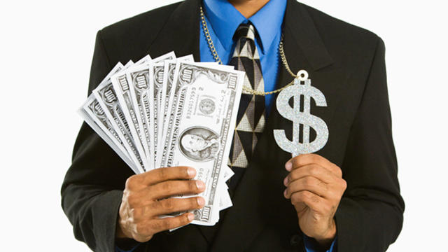 man-in-suit-wearing-necklace-with-money-sign-and-holding-cash.jpg 