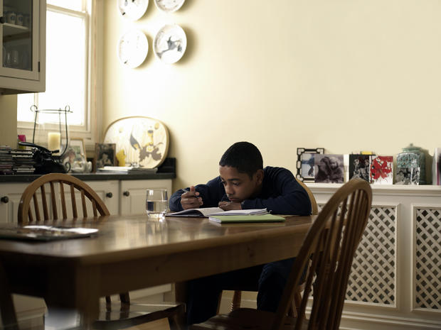 Boy (12-13) doing homework at kitchen table 